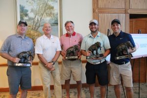 Dean of Engineering with a winning team holding elephant trophies that have their trunks down