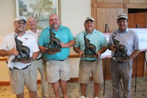 Dean of Engineering with a winning team holding elephant trophies that have their trunks up