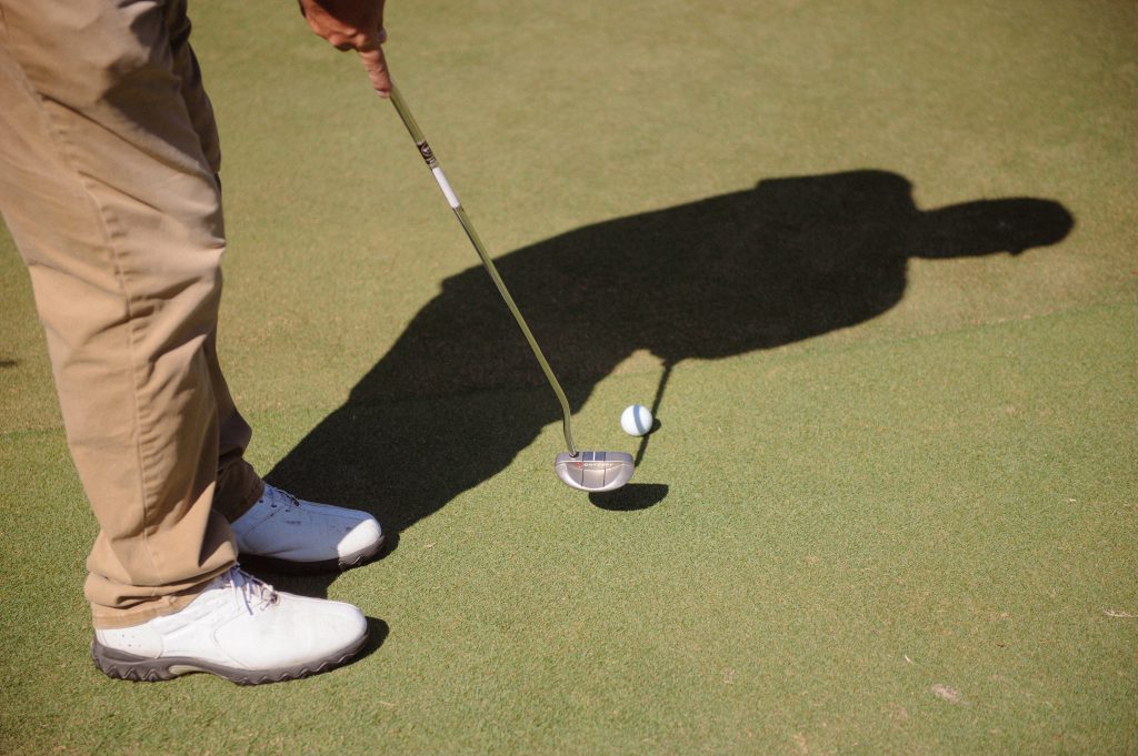 golfer's shadow on the green as he puts
