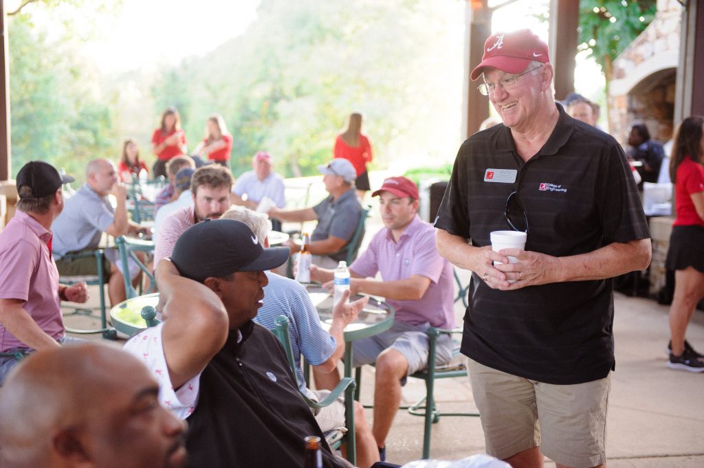 a man walking smiles at a table of people talking